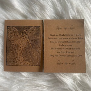 Puede incluir: Una tarjeta marrón con una ilustración en blanco y negro de una figura alada con un bastón. La tarjeta tiene texto que dice "Sing to me, Psyche the Lover, of a Love Truer than Cruel mortal minds can fathom Lend me courage to light the Lamp. to chase away The Shadow of Doubt that hides my Lover from me: May I be Loved as deeply as I Love"