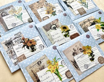 May include: A collection of blue envelopes with white polka dots decorated with vintage floral and botanical themed paper ephemera. The envelopes have handwritten text including "Plant Collector No." and "Life in little frames on what sliffthimportant".