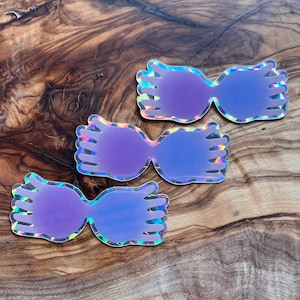 May include: Three iridescent holographic stickers of Harry Potter's glasses, shaped like hands, in shades of purple.