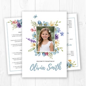 May include: Baptism invitation featuring a photo of a young girl surrounded by a floral wreath in shades of blue, purple, and pink. The text "Welcome to the Baptism of Olivia Smith" is displayed in a soft blue script.