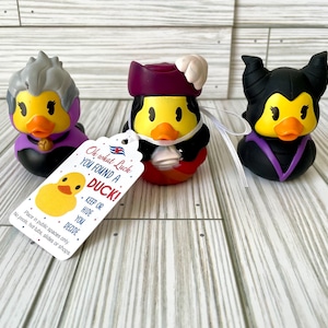 May include: Three rubber duck toys styled as Disney villains: Ursula, Jafar, and Maleficent. Each duck has a yellow body, orange beak, and is dressed in the character's signature colors. A tag reads "Oh what Luck YOU FOUND A DUCK! KEEP OR HIDE YOU DECIDE."