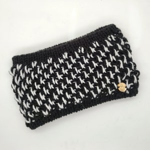 Peut inclure: Bandeau en tricot noir et blanc avec un motif pied-de-poule et un petit logo doré.