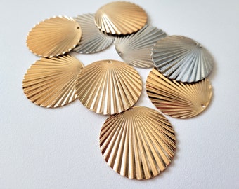 May include: A collection of gold and silver metal shell-shaped embellishments. The shells have a ribbed texture and a hole in the center.
