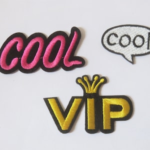Peut inclure: Trois patchs brodés thermocollants. Un patch dit "cool" dans une police cursive rose. Un autre patch dit "cool" dans une police blanche à l'intérieur d'une bulle de dialogue blanche. Le troisième patch dit "VIP" dans une police dorée avec une couronne dorée au-dessus des lettres.