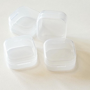 Peut inclure: Quatre contenants carrés en plastique transparent avec couvercles. Les contenants sont vides et semblent être faits d'un plastique fin et translucide.
