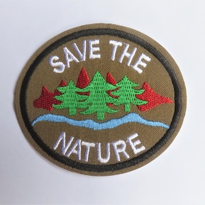 May include: A brown embroidered patch with a black border. The patch features a white outline of a wave with three green trees and red leaves. The text "SAVE THE NATURE" is embroidered in white.