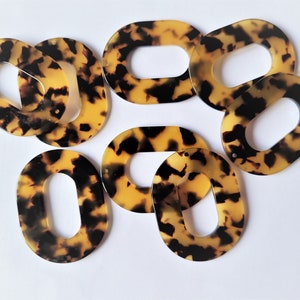 Puede incluir: Ocho anillos de plástico ovalados, con estampado marrón y negro, con un agujero en el centro.