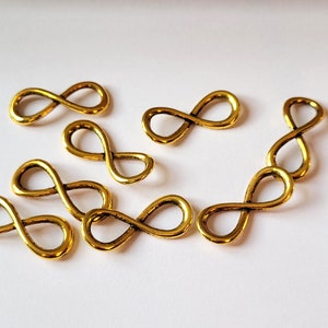 以下が含まれることがあります： 8つの金色の無限大記号チャームのセット。チャームは金属製で、滑らかで磨かれた仕上げになっています。