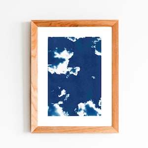 Puede incluir: Una impresión enmarcada de una imagen abstracta azul y blanca. La imagen presenta un fondo azul con nubes blancas.