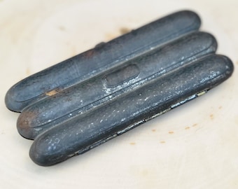 Peut inclure: Un étui à cigares en métal noir avec trois compartiments. L'étui a un aspect usé et vieilli et est légèrement bosselé.
