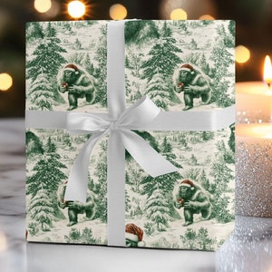 May include: A white gift wrap with a green and white pattern of a creature wearing a Santa hat in a snowy forest. The gift wrap is tied with a white ribbon.