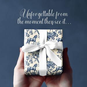 May include: A white gift box with a blue and white horse and floral pattern. The box is tied with a white ribbon and bow. The text "Unforgettable from the moment they see it..." is written above the box.