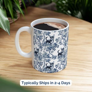 May include: White ceramic coffee mug with a blue and white pattern of a chihuahua dog in a floral design. The mug is filled with coffee.
