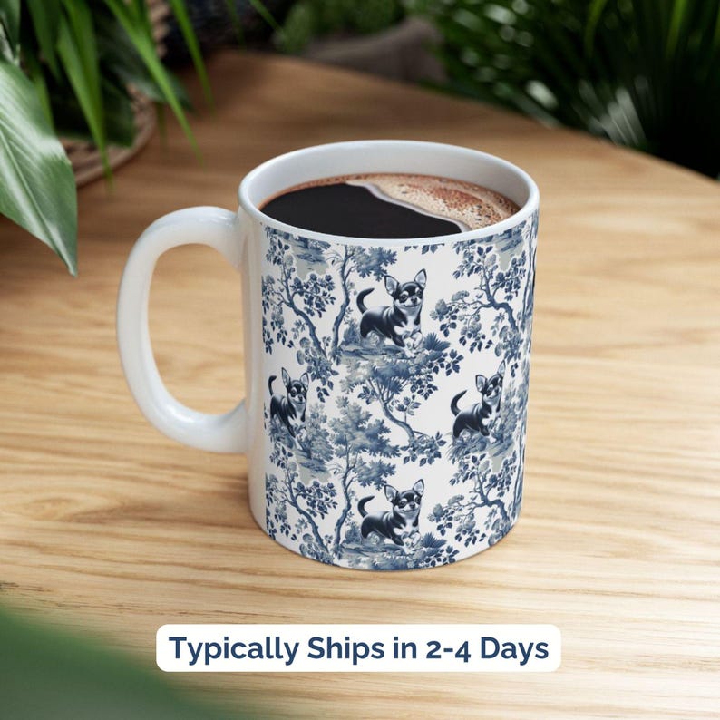 May include: White ceramic coffee mug with a blue and white pattern of a chihuahua dog in a floral design. The mug is filled with coffee.