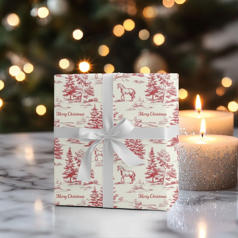 K&ouml;nnte beinhalten: Eine wei&szlig;e Geschenkbox mit einem rot-wei&szlig;en Weihnachtsdesign. Die Box ist mit einem wei&szlig;en Band und Schleife verziert. Das Design zeigt ein sich wiederholendes Muster aus B&auml;umen, Pferden und den Worten "Frohe Weihnachten".