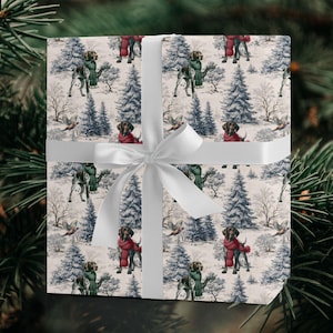 May include: Gift wrap featuring a winter scene with dogs wearing scarves. The dogs are brown and white, and the scarves are red and green. The background includes snow-covered trees and flying birds. A white ribbon is tied around the gift.