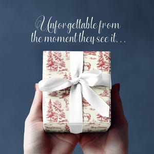 K&ouml;nnte beinhalten: Eine wei&szlig;e Geschenkbox mit einem roten und wei&szlig;en Muster aus B&auml;umen und Pferden. Die Box ist mit einem wei&szlig;en Band und einer Schleife gebunden. Der Text "Merry Christmas" ist auf der Unterseite der Box aufgedruckt.