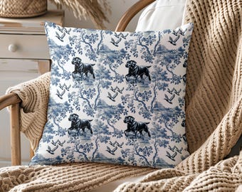May include: A square throw pillow featuring a white background with a repeating blue toile pattern. The design displays black Labrador dogs standing among detailed blue trees and foliage, interspersed with small flying birds throughout the print.