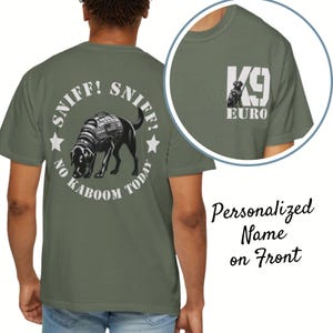 May include: Olive green t-shirt featuring a black dog graphic with the text "SNIFF! SNIFF! NO KABOOM TODAY" in a circular design. A smaller graphic on the sleeve reads "K9 EURO". The shirt is designed for personalization.