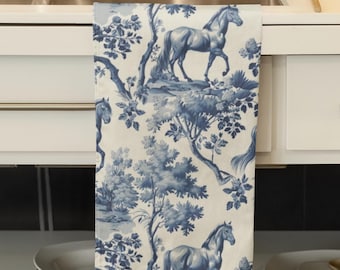 May include: Blue and white kitchen towel with a pattern of horses and trees. The towel is hanging on a white cabinet.