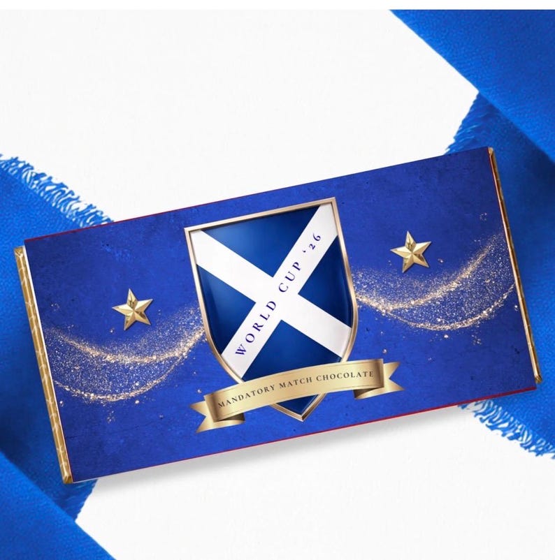 May include: A blue chocolate bar with gold trim and accents. The bar features a shield with a white cross and the text "WORLD CUP '26". Gold stars and the text "MANDATORY MATCH CHOCOLATE" are also visible on the bar.