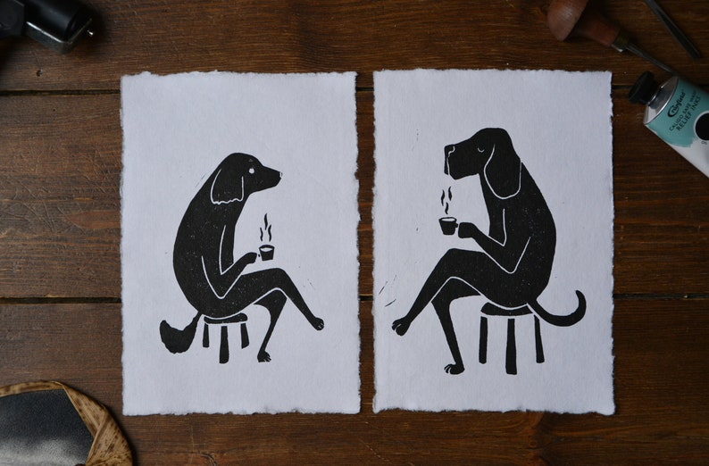May include: Two black and white illustrations of dogs sitting on stools and holding cups of coffee. The dogs are facing each other and appear to be having a conversation.