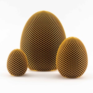 Könnte beinhalten: Drei goldfarbene Deko-Eier mit geometrischem Muster. Die Eier sind in einer Reihe vom größten zum kleinsten angeordnet.