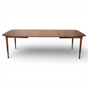 May include: A rectangular wooden dining table with a light brown finish. The table has a curved edge and four slender, tapered legs. The table is approximately 72 inches long and 36 inches wide.