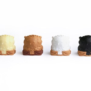 Puede incluir: Cuatro peque&ntilde;as figuras de b&uacute;ho en fila. Los b&uacute;hos son de color crema, marr&oacute;n, blanco y negro. Cada uno tiene un cuerpo texturizado y se asienta sobre una base marr&oacute;n. El fondo es blanco liso.
