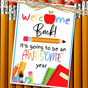 Pode incluir: Um sinal de boas-vindas de volta &agrave; escola imprim&iacute;vel com uma ma&ccedil;&atilde; vermelha, l&aacute;pis e um caderno. O sinal diz "Welcome Back! It's going to be an AWESOME year."