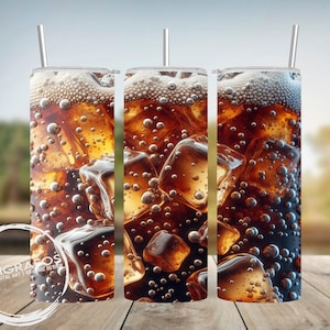 May include: Three stainless steel tumblers with a design of ice cubes and cola. The tumblers are filled with a dark brown liquid and have a straw in each.