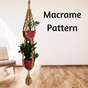 May include: A macrame plant hanger with two hanging pots, one with green plants and the other with purple flowers. The hanger is made of natural rope and has a tassel at the bottom. The text "Macrame Pattern" is written in black on a white background.
