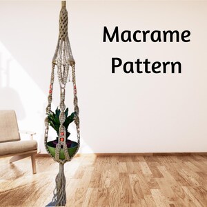 May include: Macrame plant hanger with a beige rope and red beads. The hanger is holding a small green plant in a brown pot. The hanger is hanging from the ceiling in a room with a wooden floor.