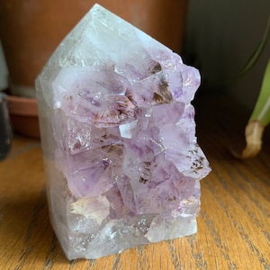 May include: A large, clear quartz crystal point with a cluster of amethyst crystals inside. The amethyst crystals are a deep purple color and have a few brown inclusions.