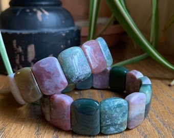 May include: Two bracelets made of colorful agate stones. The bracelets are made of rectangular shaped stones in shades of green, pink, and brown. The bracelets are stacked on top of each other.