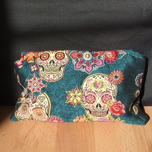 Peut inclure: Pochette en tissu bleu sarcelle avec un motif floral et cr&acirc;ne color&eacute;. Les cr&acirc;nes ont des d&eacute;tails roses, jaunes et blancs.