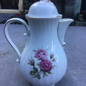 May include: White porcelain coffee pot with a gold trim and a floral design featuring pink roses. The lid has a small frog finial.