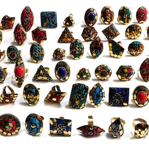 May include: A selection of decorative rings with mosaic patterns in a variety of shapes. The rings have gold-coloured bands and settings, with colourful stones in red, blue, green, and yellow. They are displayed on a white background.