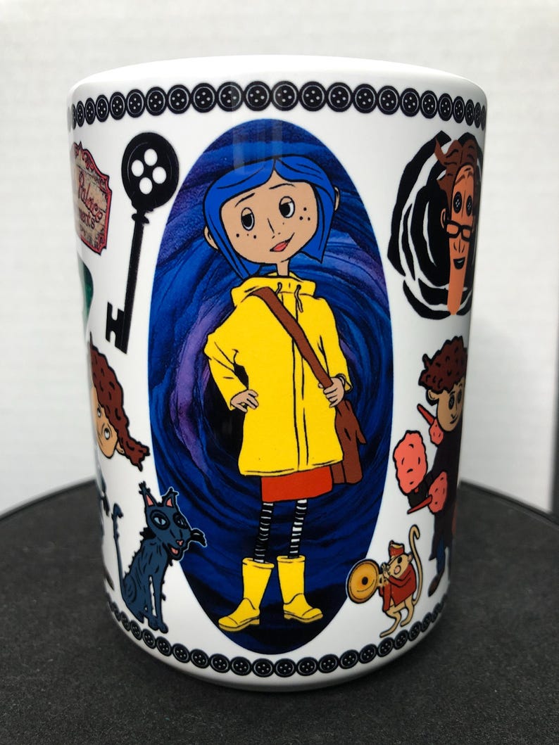 May include: White ceramic mug featuring illustrations from the animated film. The central image is of a girl in a yellow raincoat and boots, surrounded by other characters and imagery from the movie. The top and bottom of the mug are decorated with black button designs.