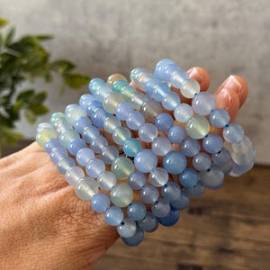 Puede incluir: Una pila de pulseras de piedras preciosas azules y verdes con cuentas redondas. Las pulseras est&aacute;n hechas de piedras naturales y son perfectas para superponer.