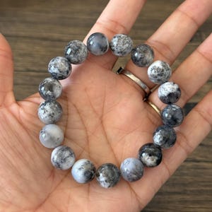 May include: A bracelet made of round, white and black, speckled beads.