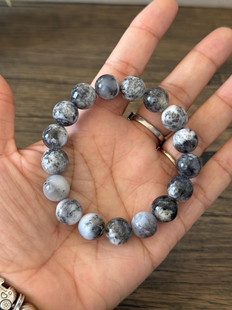 May include: A bracelet made of round, white and black, speckled beads.