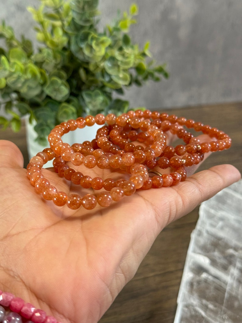 May include: A stack of orange sunstone bead bracelets. The bracelets are made with small, round beads and have a natural, earthy look.