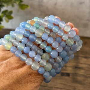 Puede incluir: Una pila de pulseras de cuentas de &aacute;gata azul. Las pulseras est&aacute;n hechas con cuentas redondas y lisas en varios tonos de azul, de claro a oscuro.