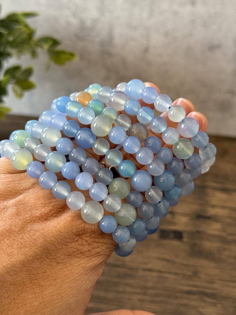 Puede incluir: Una pila de pulseras de cuentas de &aacute;gata azul. Las pulseras est&aacute;n hechas con cuentas redondas y lisas en varios tonos de azul, de claro a oscuro.