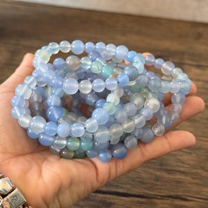 Puede incluir: Un conjunto de pulseras de cuentas de &aacute;gata azul claro. Las pulseras est&aacute;n hechas con cuentas redondas y lisas y son de color azul claro.