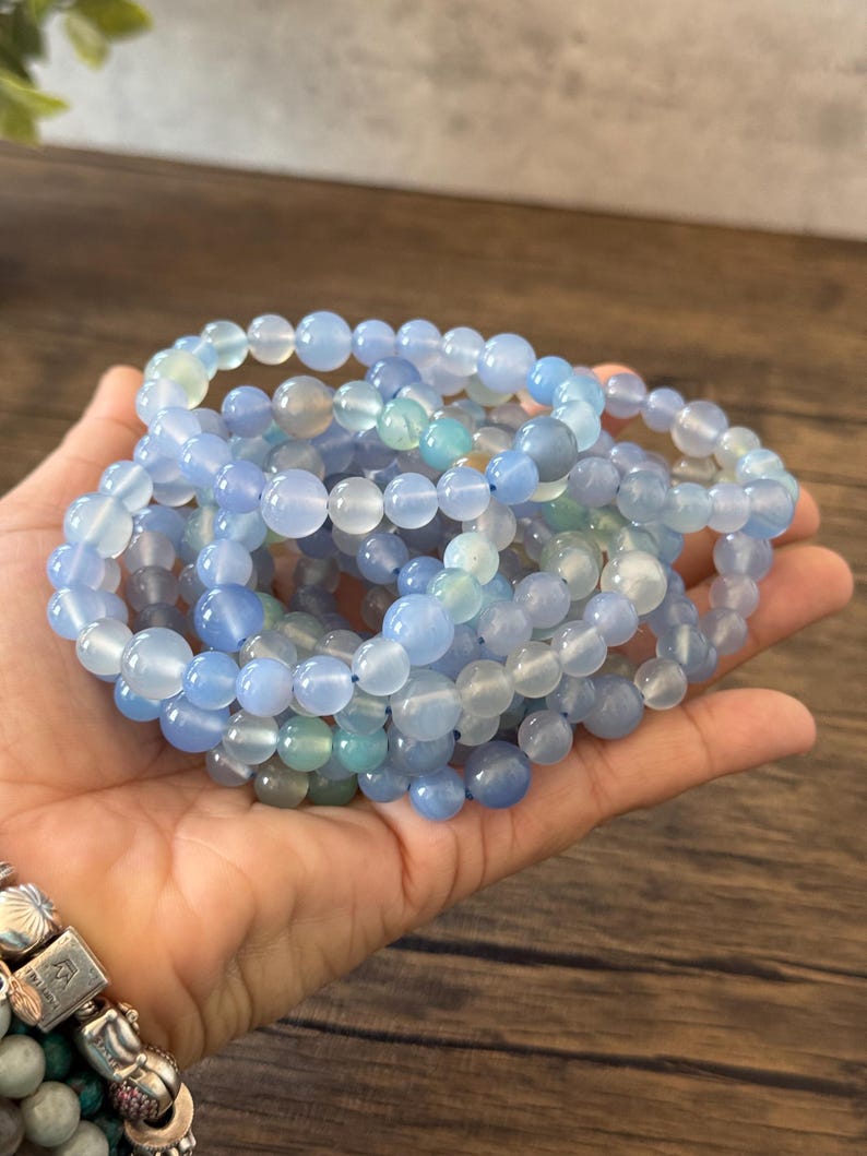 Puede incluir: Un conjunto de pulseras de cuentas de &aacute;gata azul claro. Las pulseras est&aacute;n hechas con cuentas redondas y lisas y son de color azul claro.
