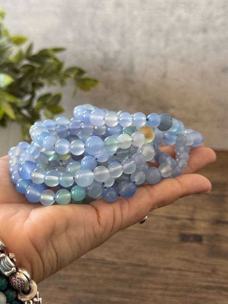 Puede incluir: Una pila de pulseras de cuentas de &aacute;gata azul. Las cuentas son redondas y lisas, y las pulseras est&aacute;n hechas con el&aacute;stico.