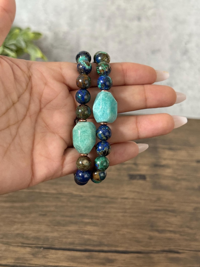 May include: Two bracelets made of blue, green, and brown gemstone beads. The bracelets feature larger, faceted, turquoise-colored beads.