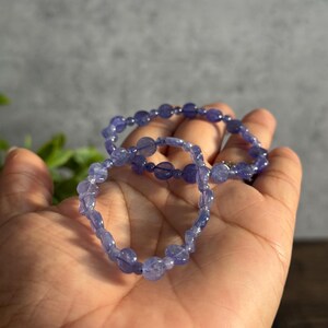 Puede incluir: Dos pulseras de piedras preciosas moradas con cuentas redondas.